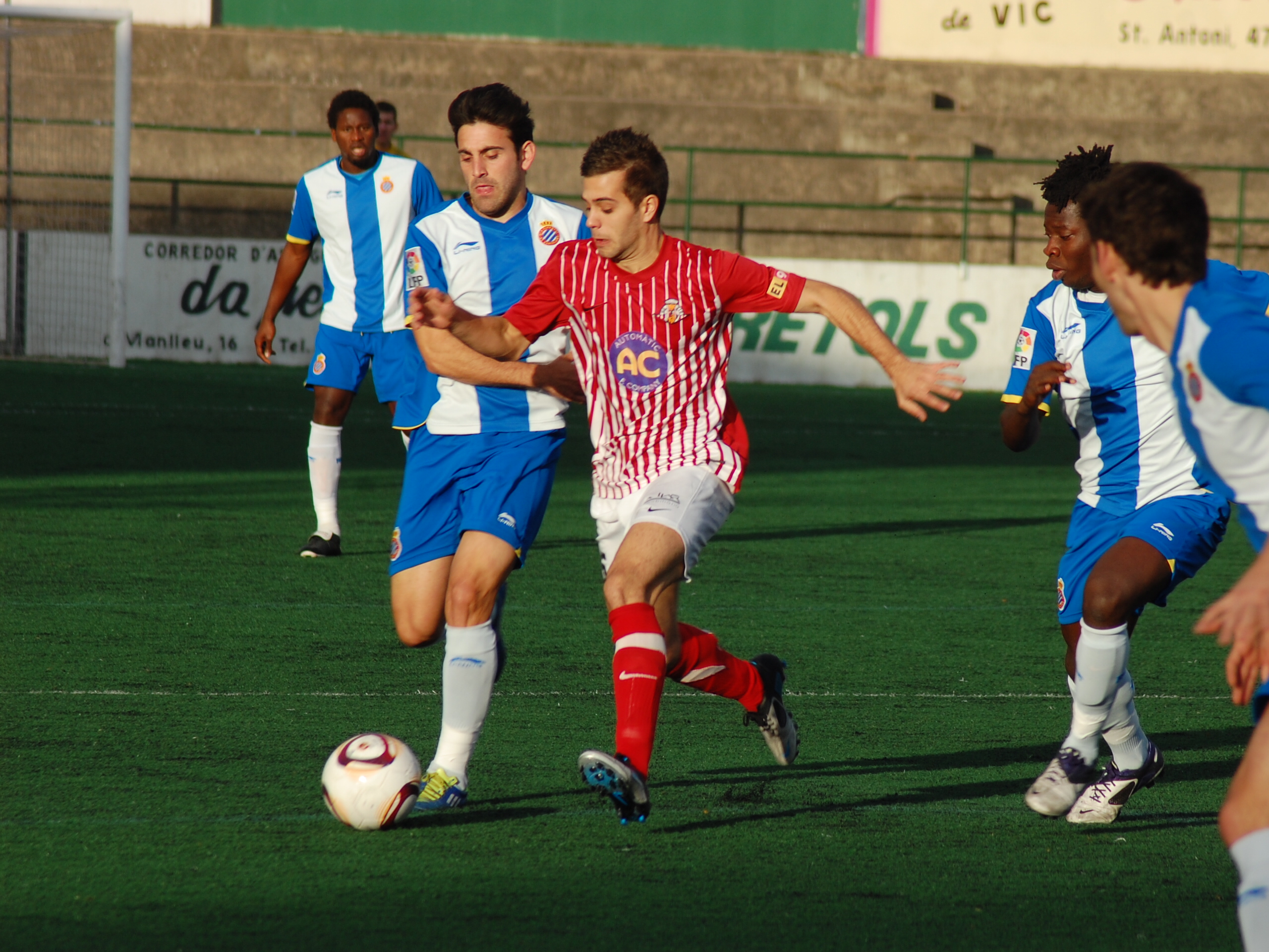 Pol Coll controla l'esfèrica, pressionat pels jugadors balnc-i-blaus. FOTO: Jordi de Planell.