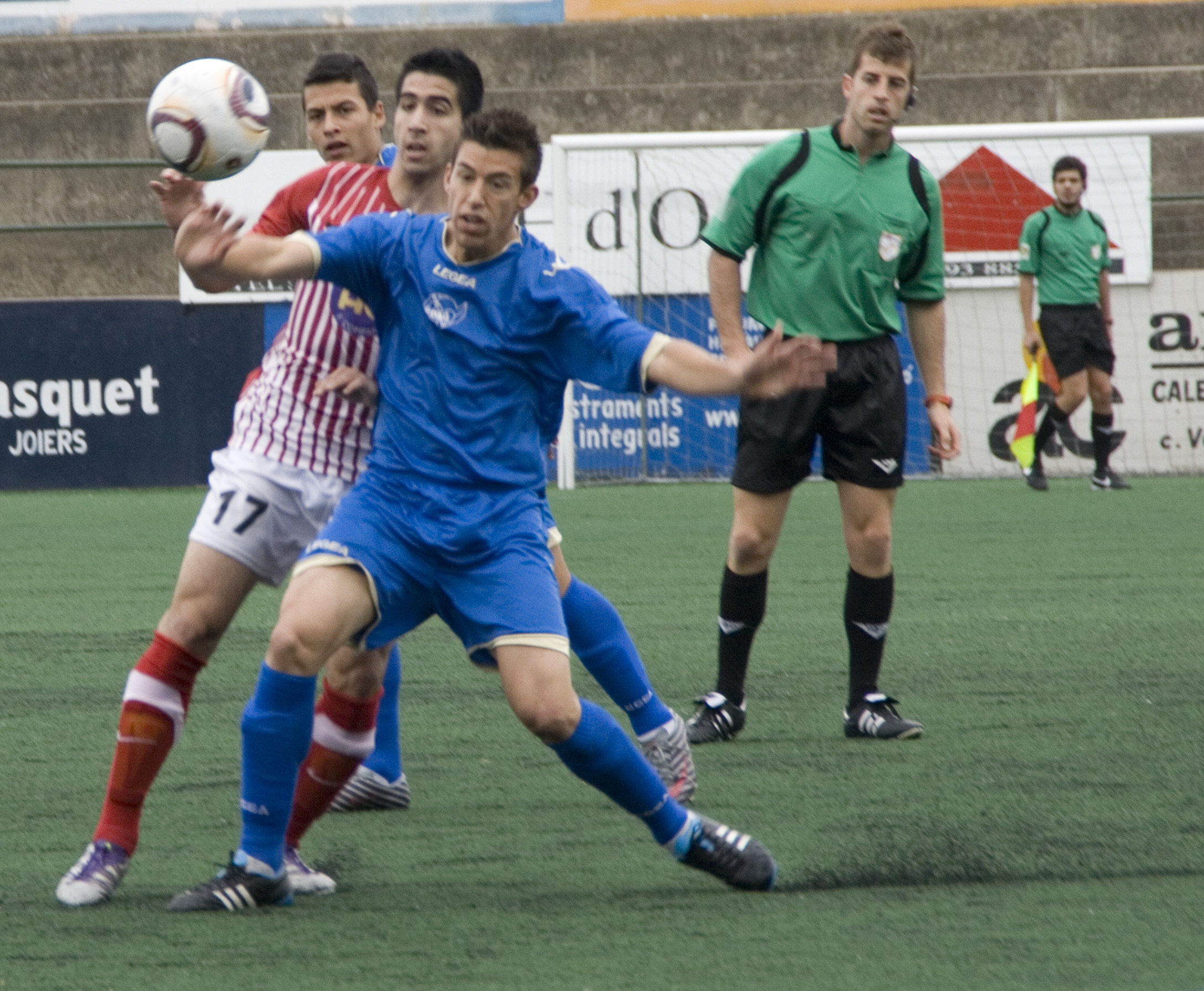 Poves intenta interceptar la pilota davant l'atenta mirada del col·legiat del partit. FOTO: Jordi Cutrina.